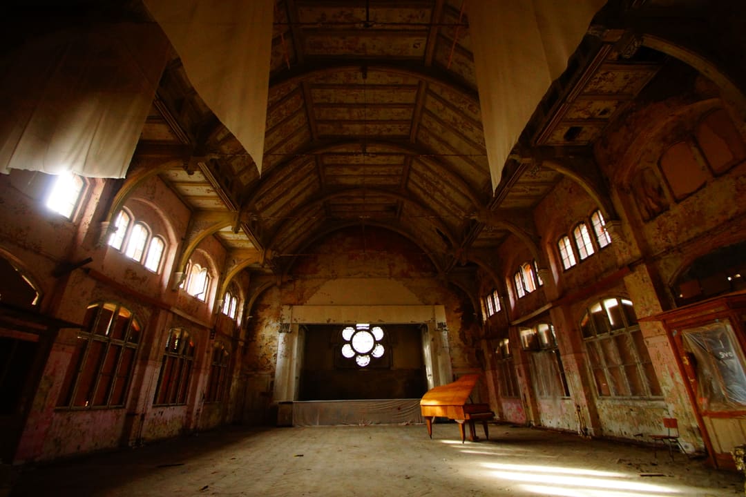 Abandoned grand piano hall with ornate rosette window, atmospheric urban exploration photography by Ralf