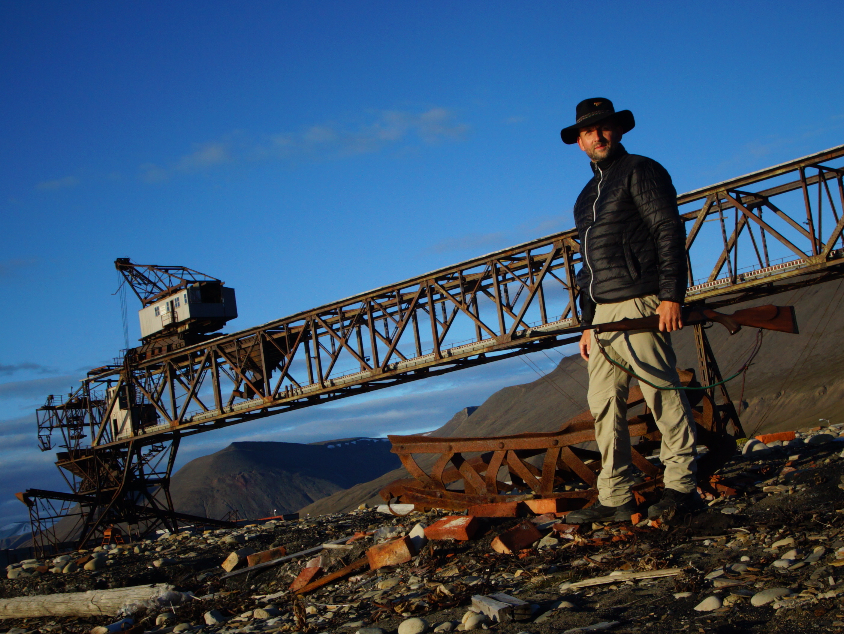 Ralf, urban exploration photographer, standing at an abandoned Soviet-era industrial crane structure in Pyramiden, Svalbard, Norway